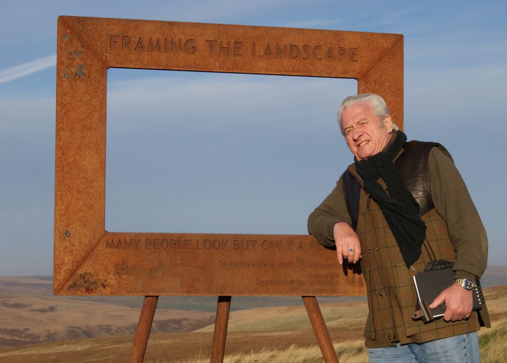 Watercolour Artist Ashley Jackson stands in front of the first installation of Framing the Landscape a free standing metal frame through which you can view the landscape on Marsden Moor above Holmfirth, West Yorkshire